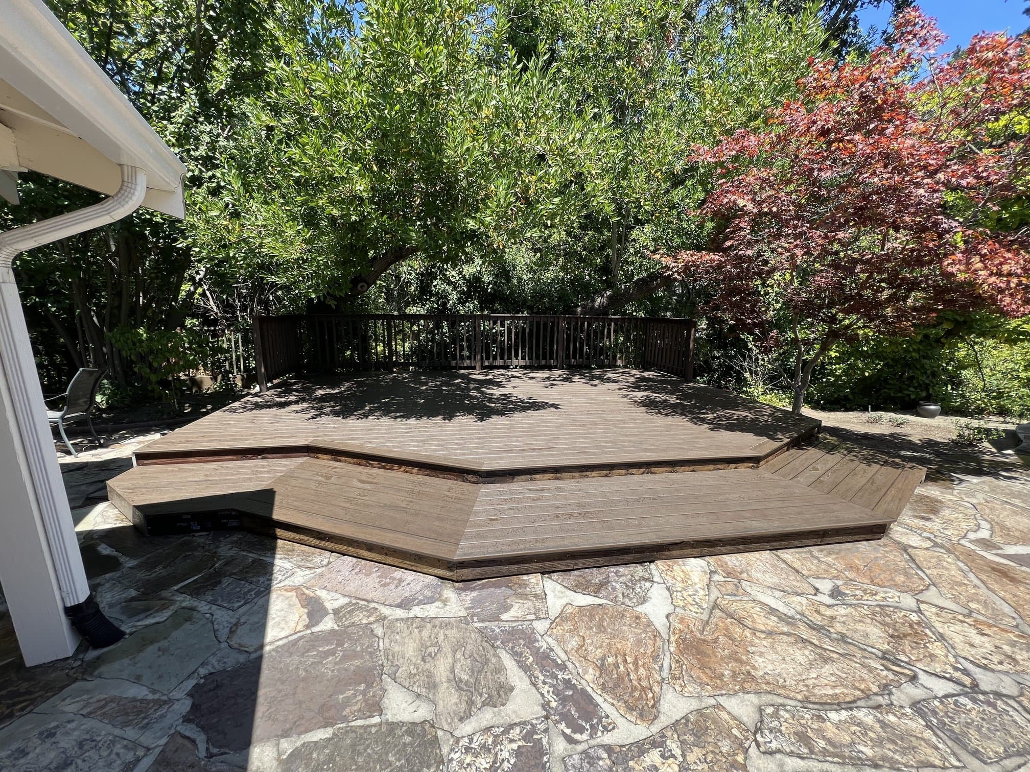 Composite deck stepping down to a flagstone patio in a backyard