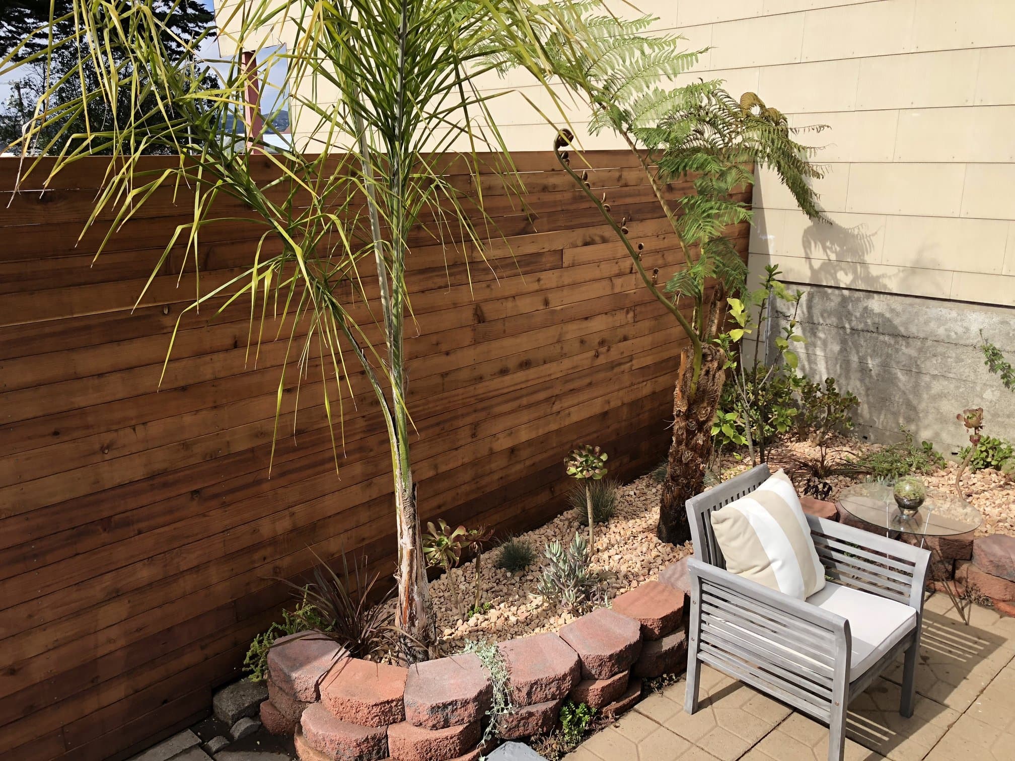 Horizontal fence bordering a paver patio with landscaping