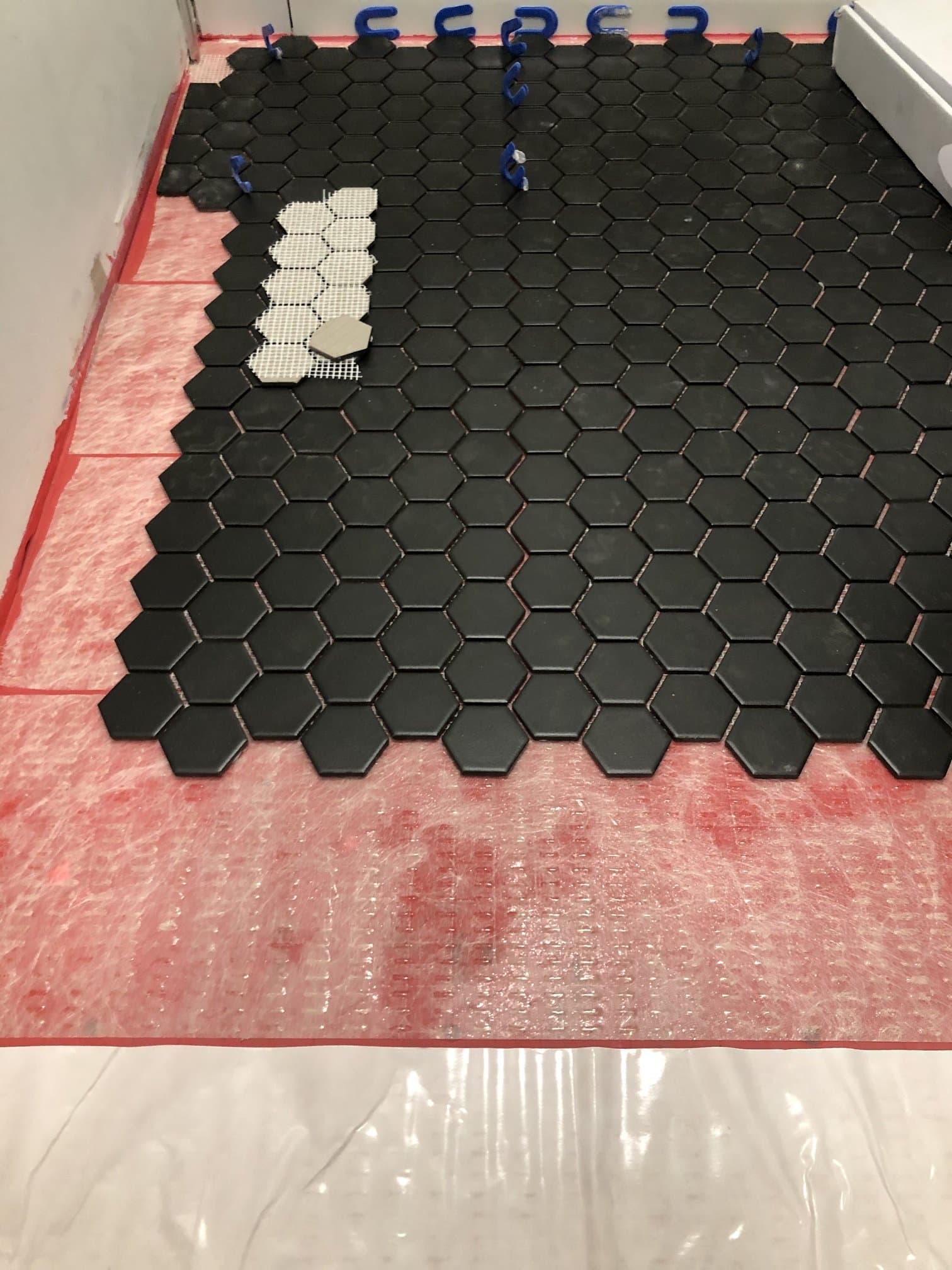 Black hex mosaic bathroom floor during waterproofing and tile set