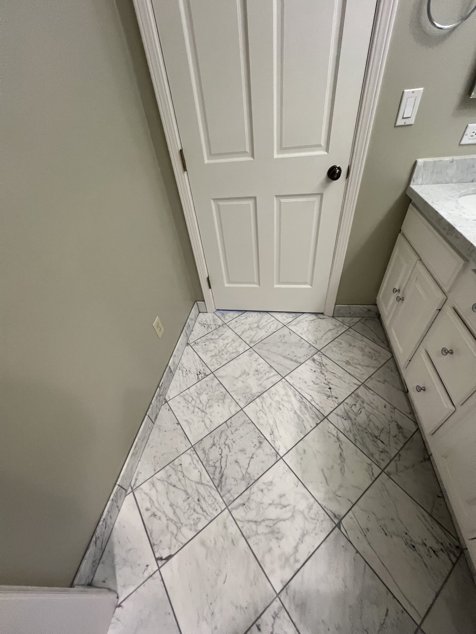 Diagonal marble tile floor in a bathroom with white cabinets