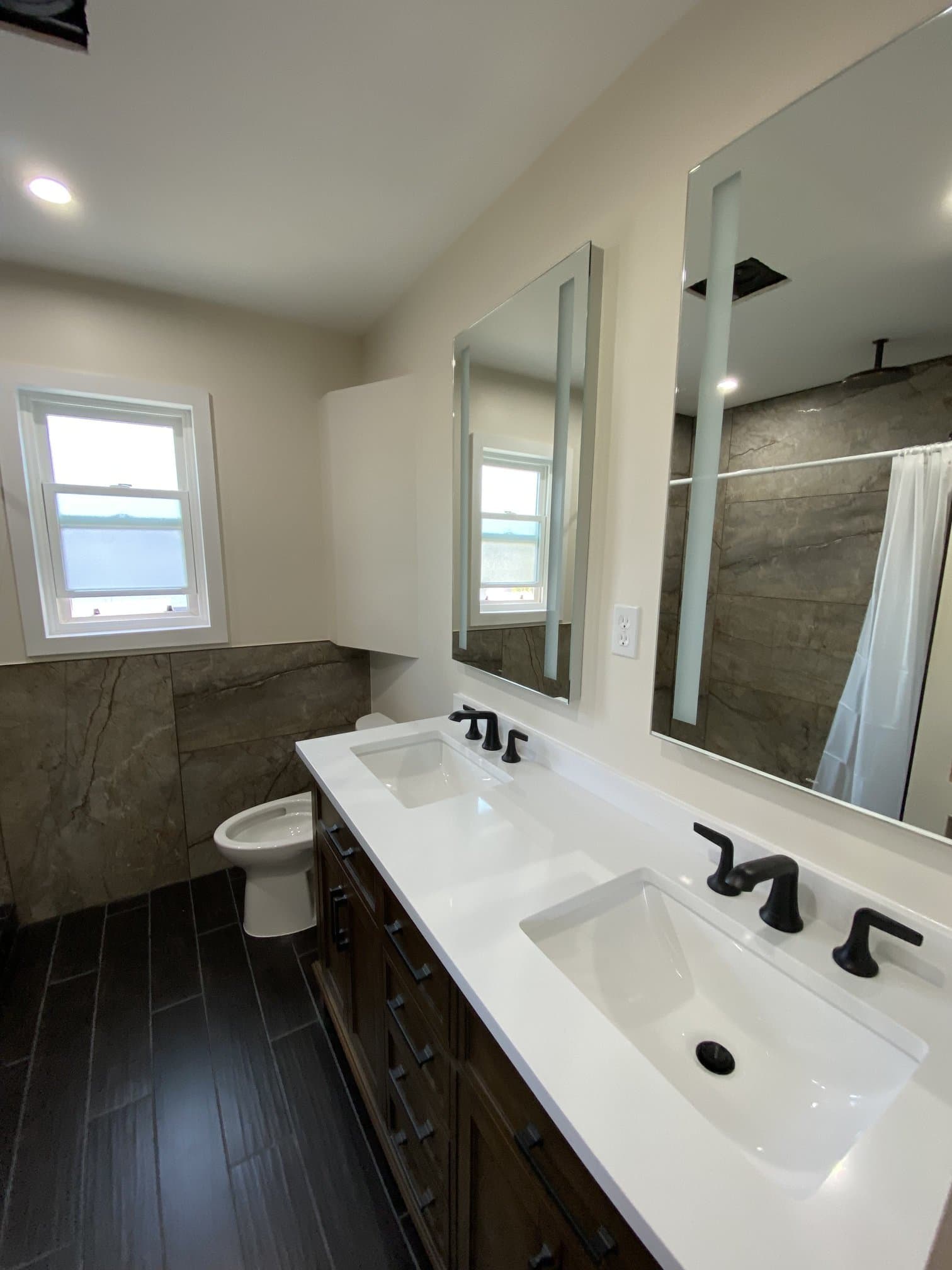 Double vanity with white quartz top against large-format stone tile walls