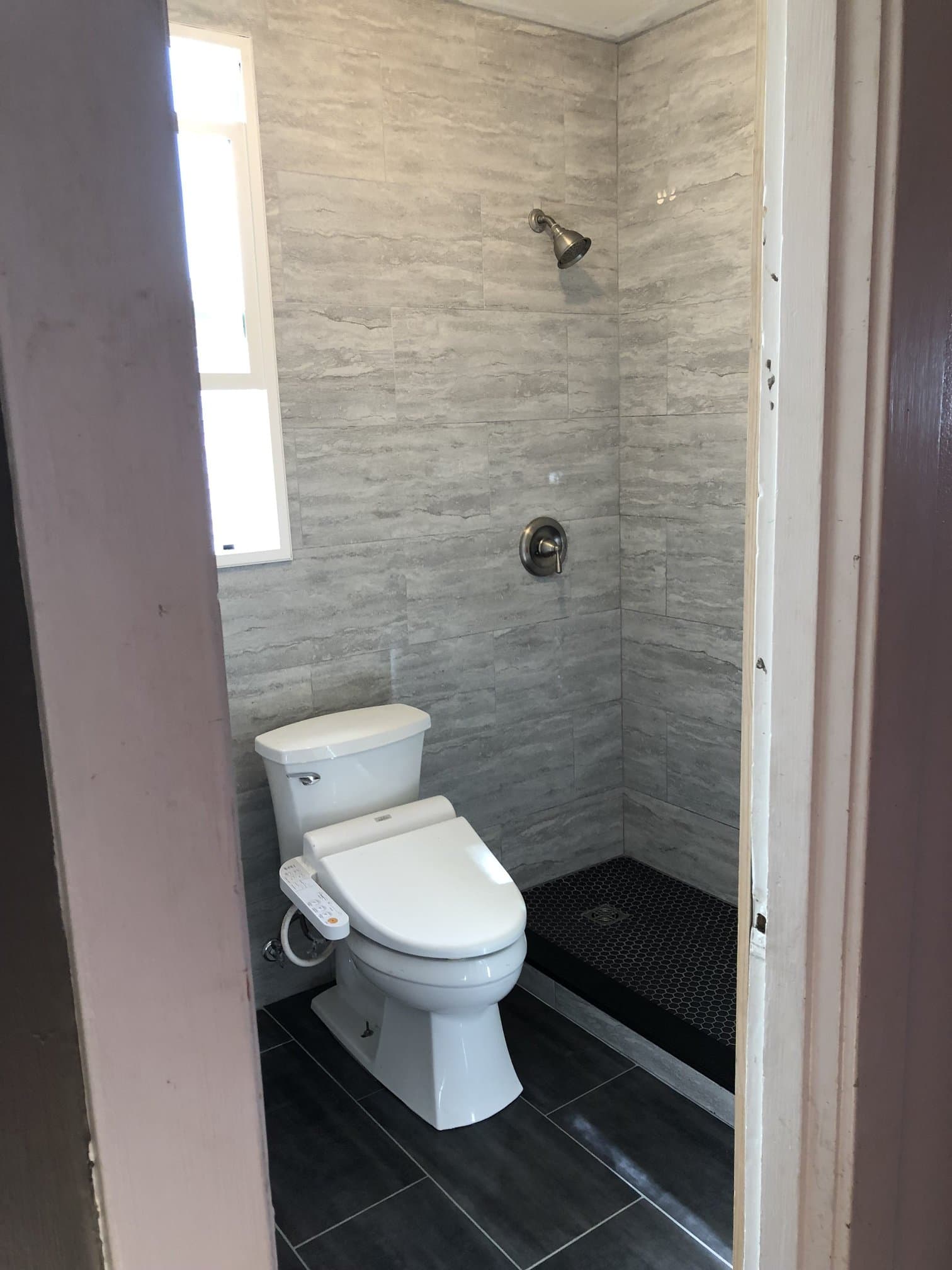 Gray tile bathroom with walk-in shower and toilet