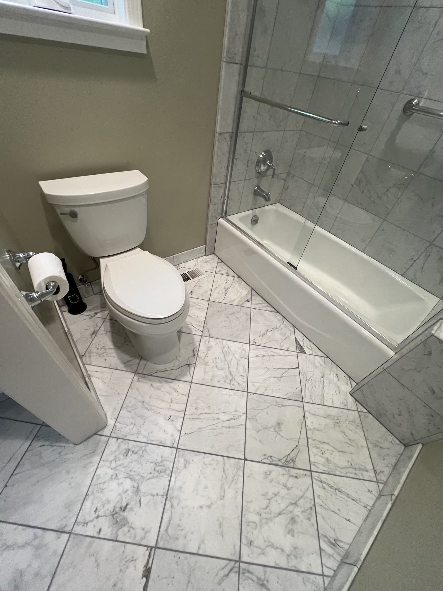Marble-tiled tub and shower with a glass door