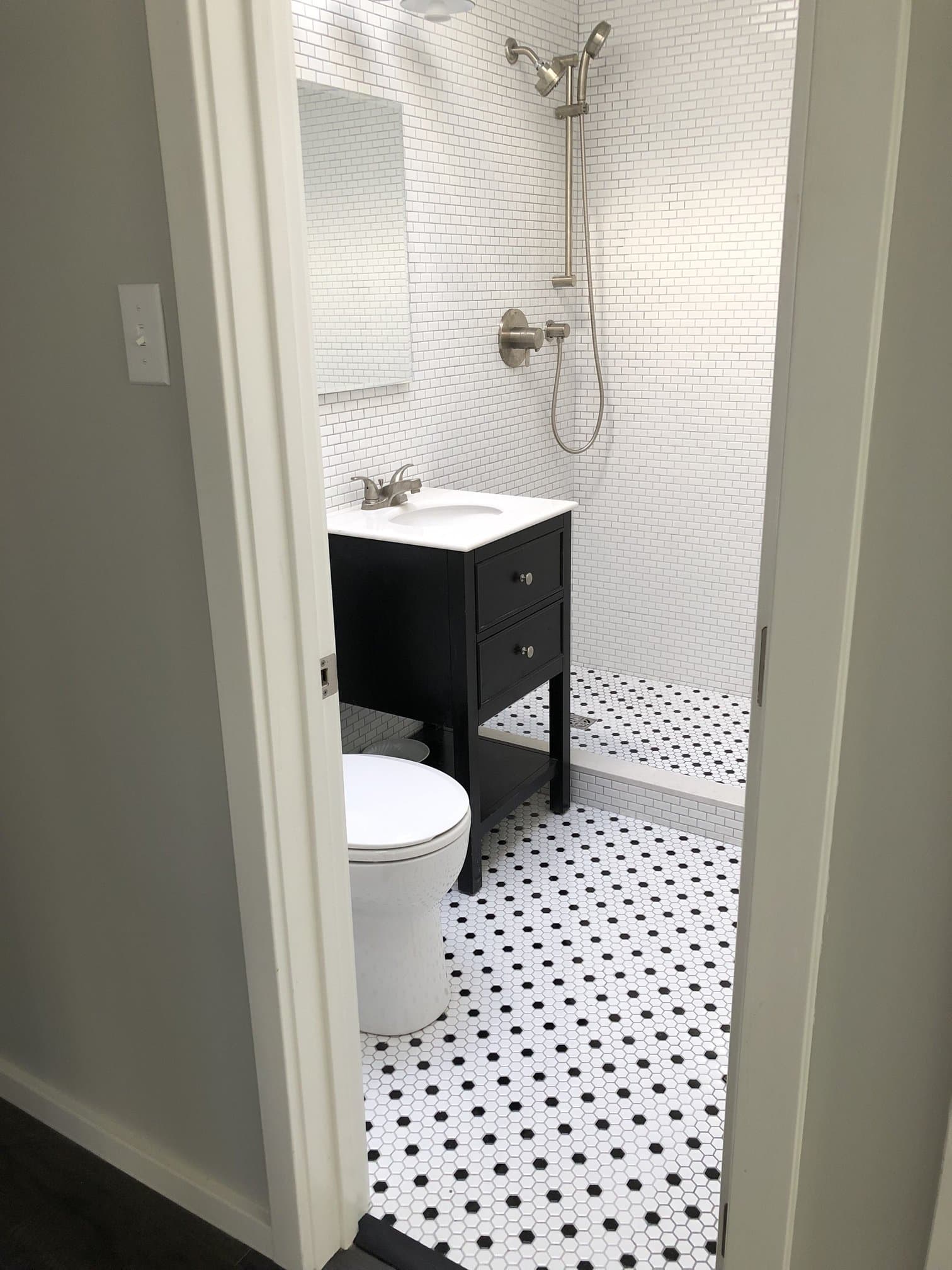 Black and white subway tile bathroom with walk-in shower, dark vanity, and chrome fixtures.