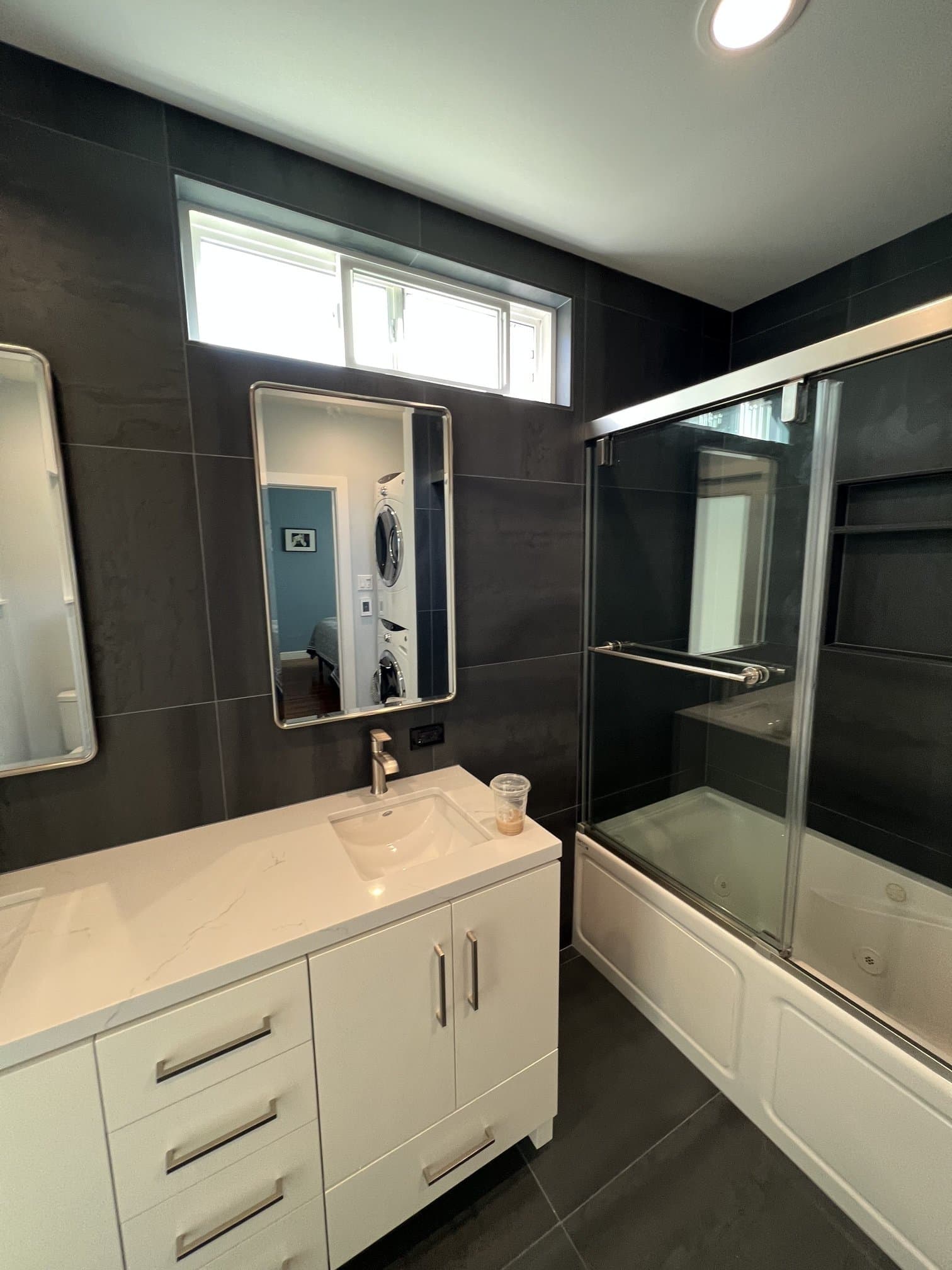 Bathroom vanity beside dark tile walls and a glass shower