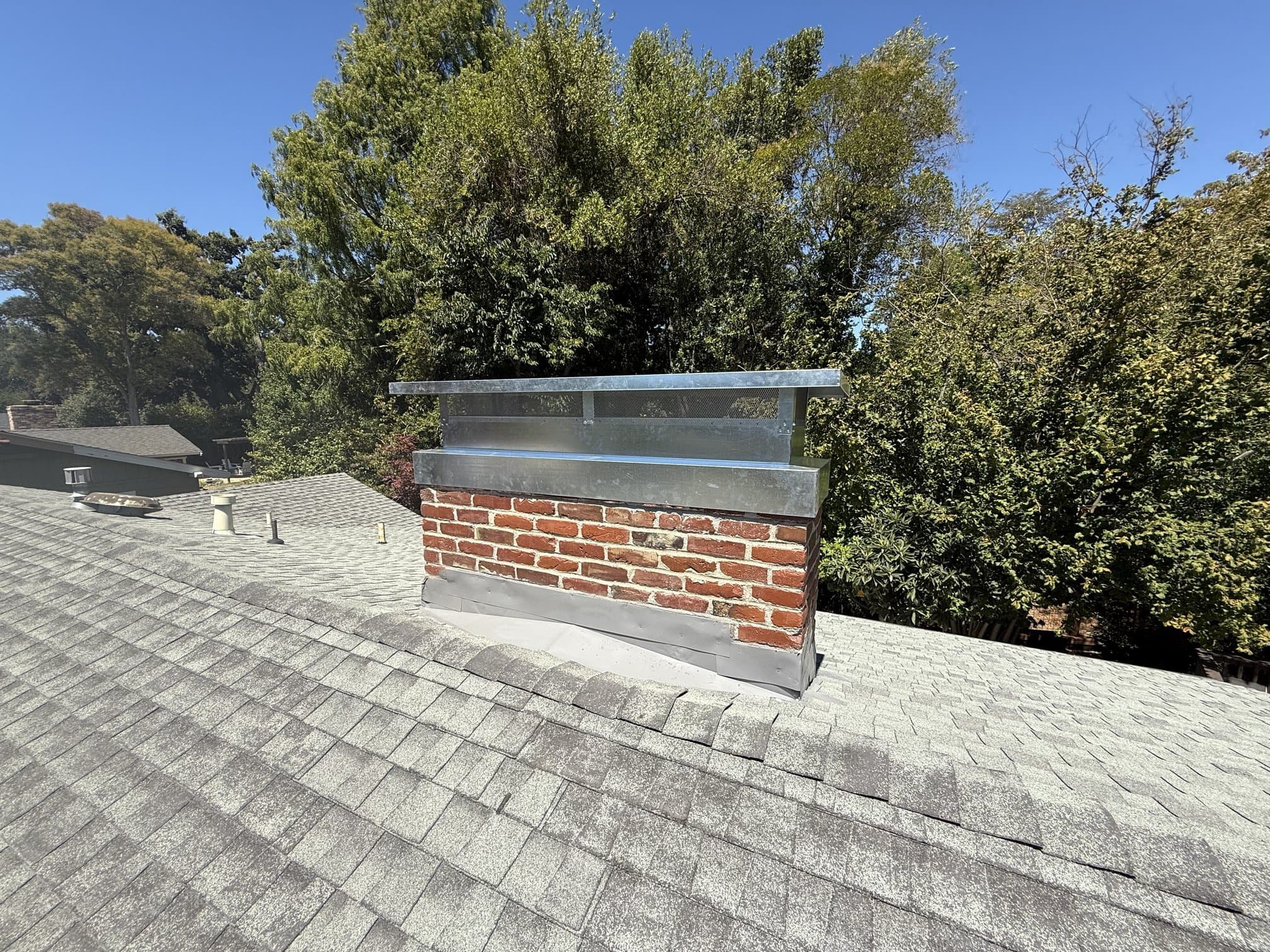 Brick chimney with metal cap and roof flashing