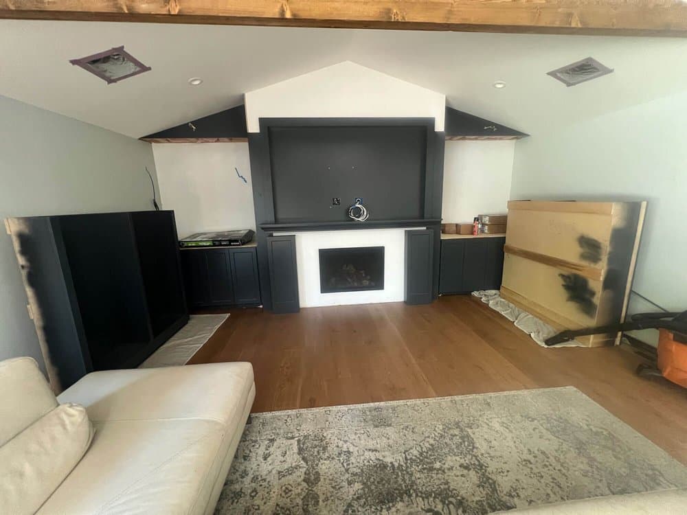 Nearly finished charcoal built-in with a white fireplace surround, TV niche, and side cabinets