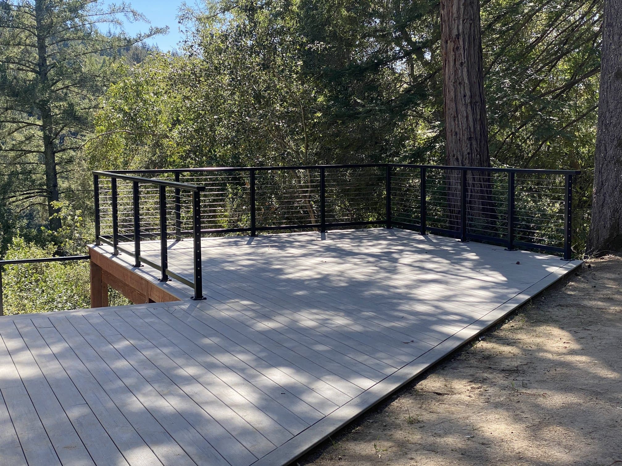 Composite deck with black cable railing overlooking woods
