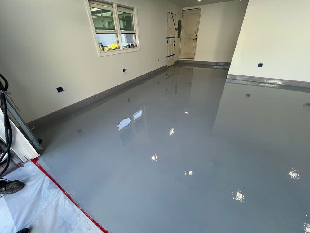 Fresh solid gray epoxy coat on a garage floor before the flake finish