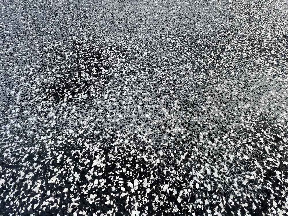 Close-up of a finished charcoal and white flake epoxy garage floor