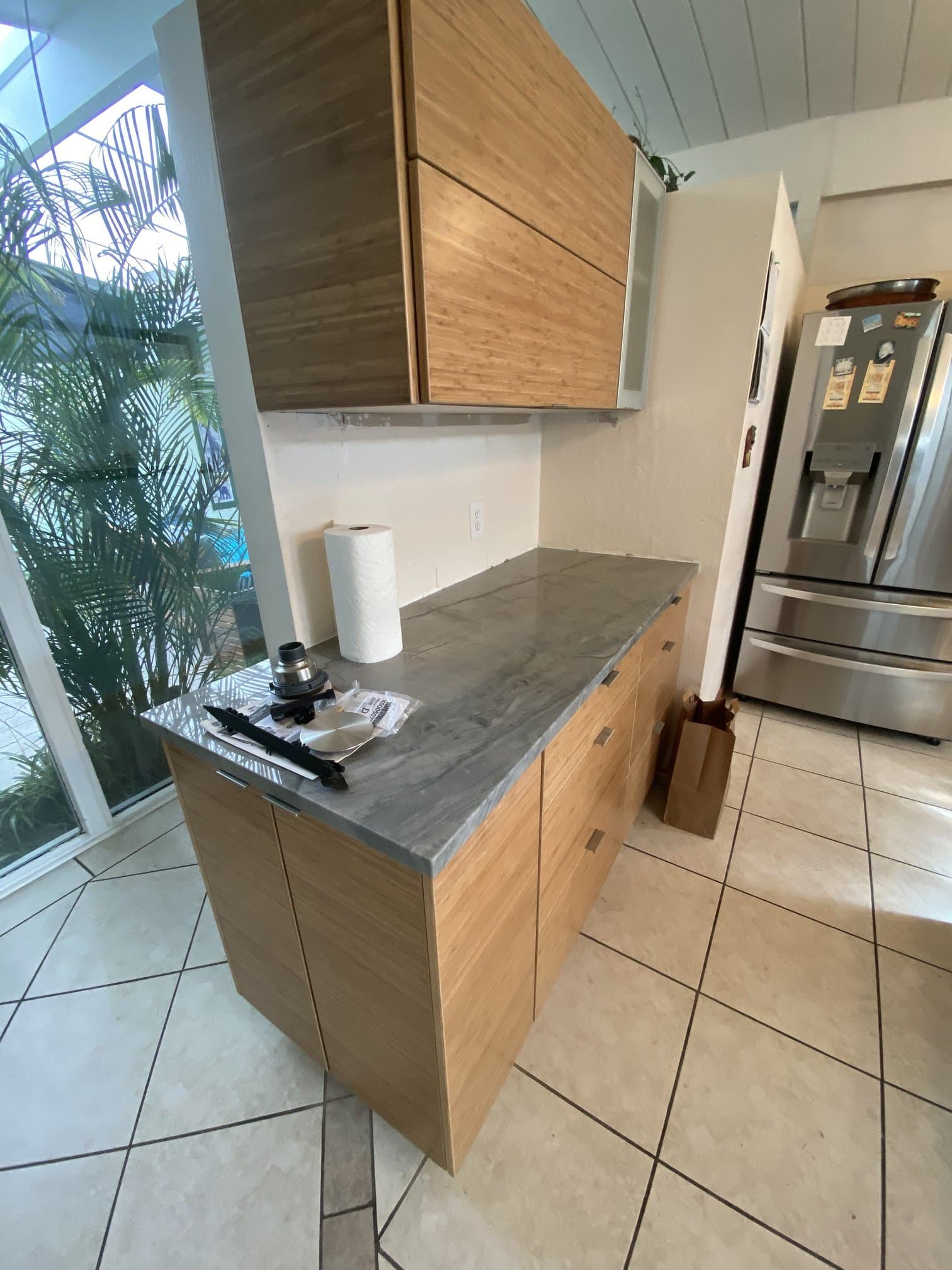 Bamboo cabinets with grey veined stone countertop and frosted-glass upper doors