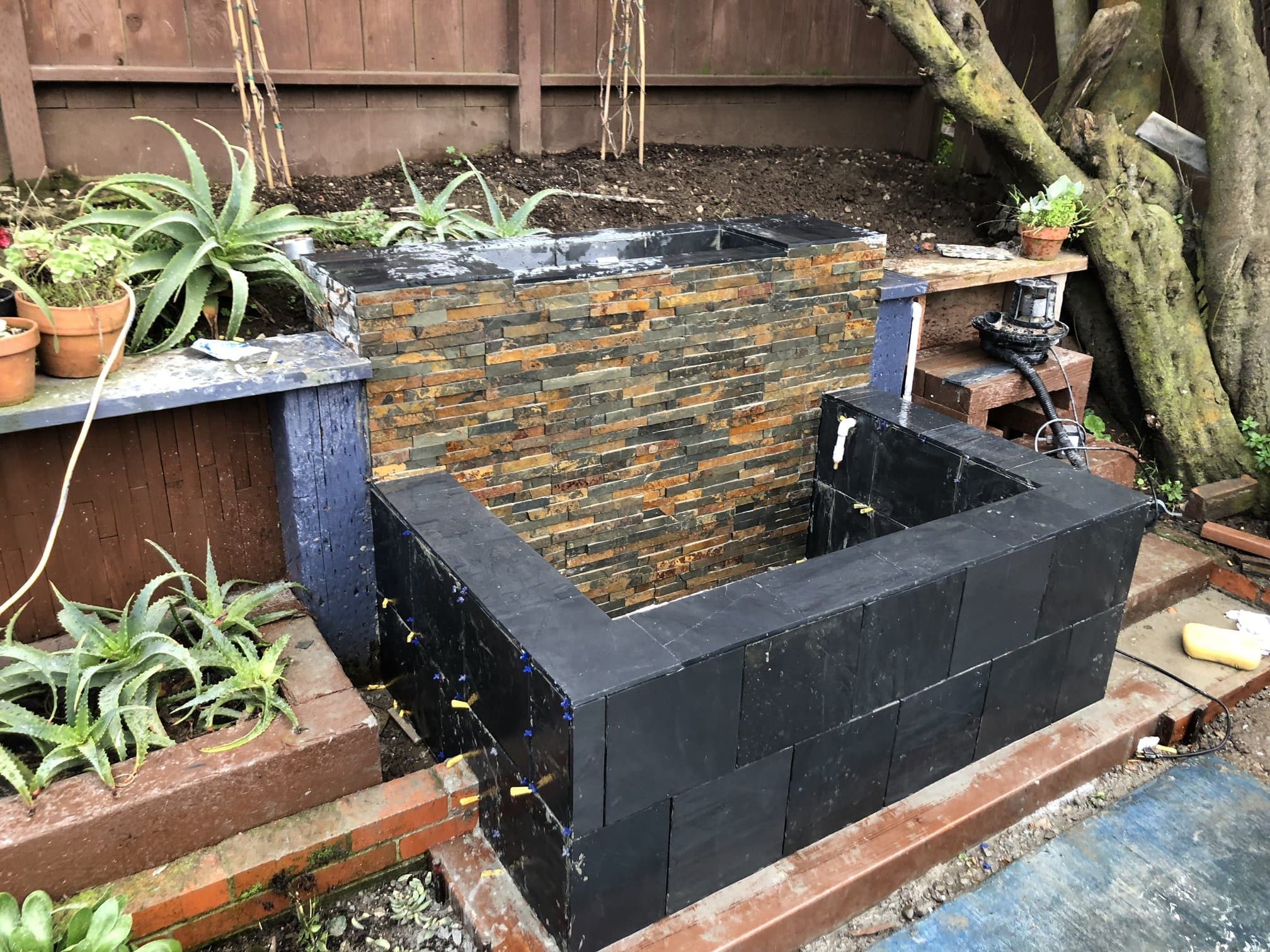 Outdoor fountain basin clad in ledger stone and slate