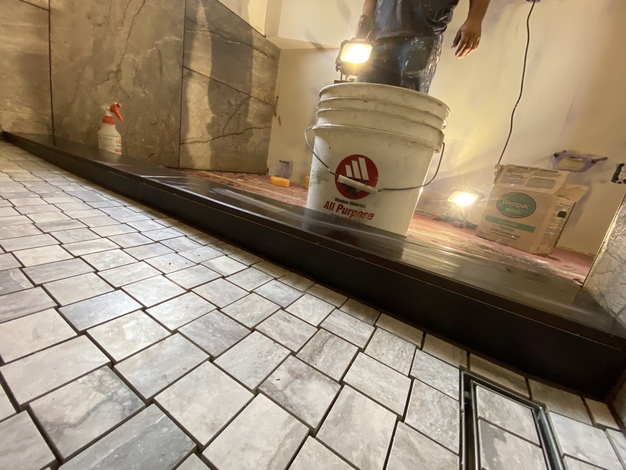 Shower mosaic floor, linear drain, and tiled curb detail