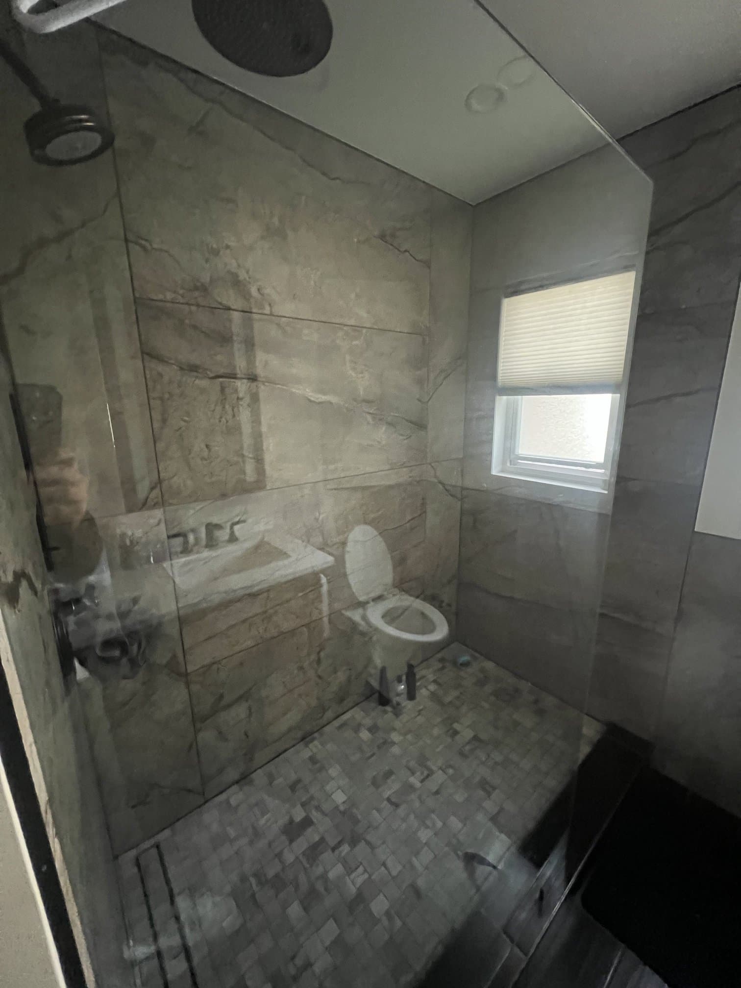 Walk-in shower finished in marble-look tile with glass enclosure