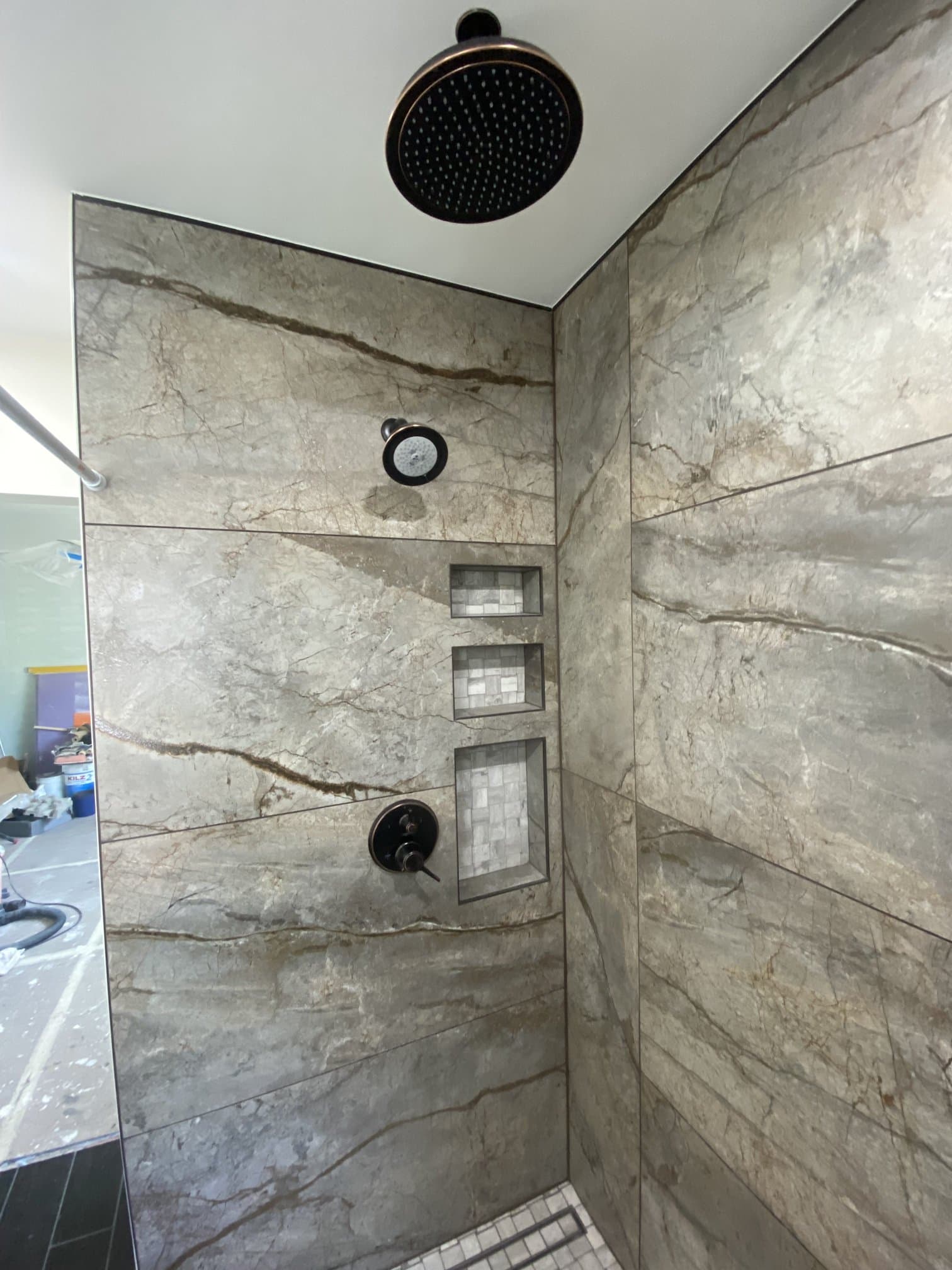 Walk-in stone-tile shower with recessed niches and finished fixtures